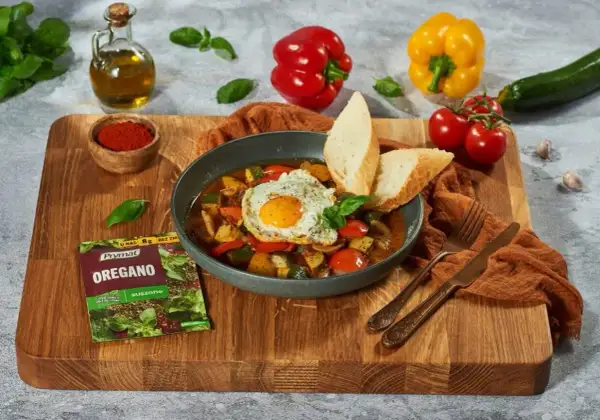 Pyszne pisto manchego z jajkiem sadzonym i pieczywem, doprawione oregano.