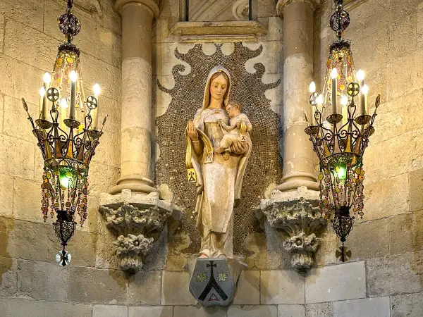 Figurka Matki Boskiej z Dzieciątkiem, otoczona ozdobnymi żyrandolami, to jeden z wielu detali, które warto odkryć w Sagrada Familia. Ciekawostki architektoniczne zachwycają.