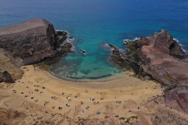 Zatoka Papagayo na Lanzarote, z turkusową wodą i piaszczystą plażą, gdzie odpoczywają turyści.